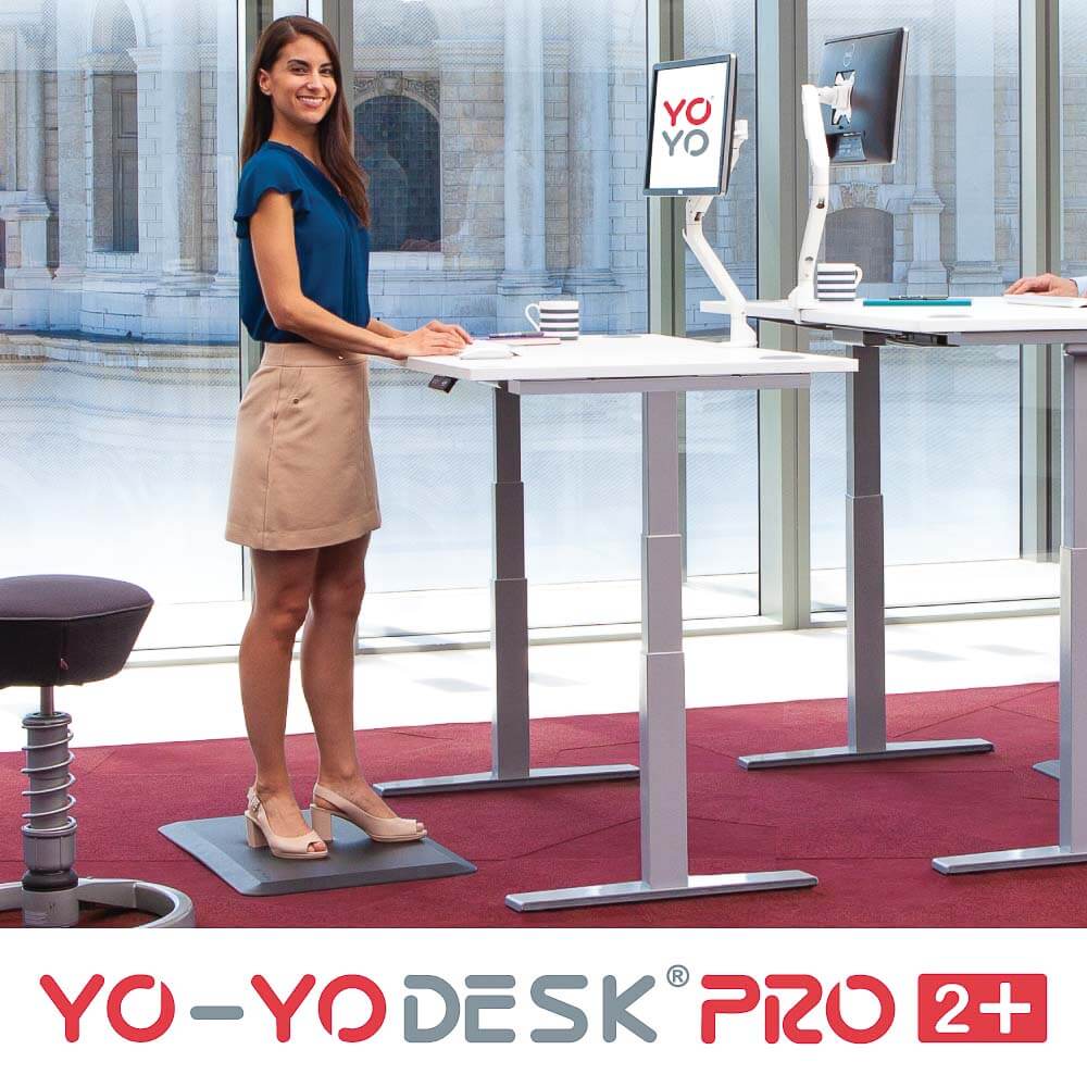 A woman using a dual motor electric standing desk in an office, showcasing modern ergonomic design.