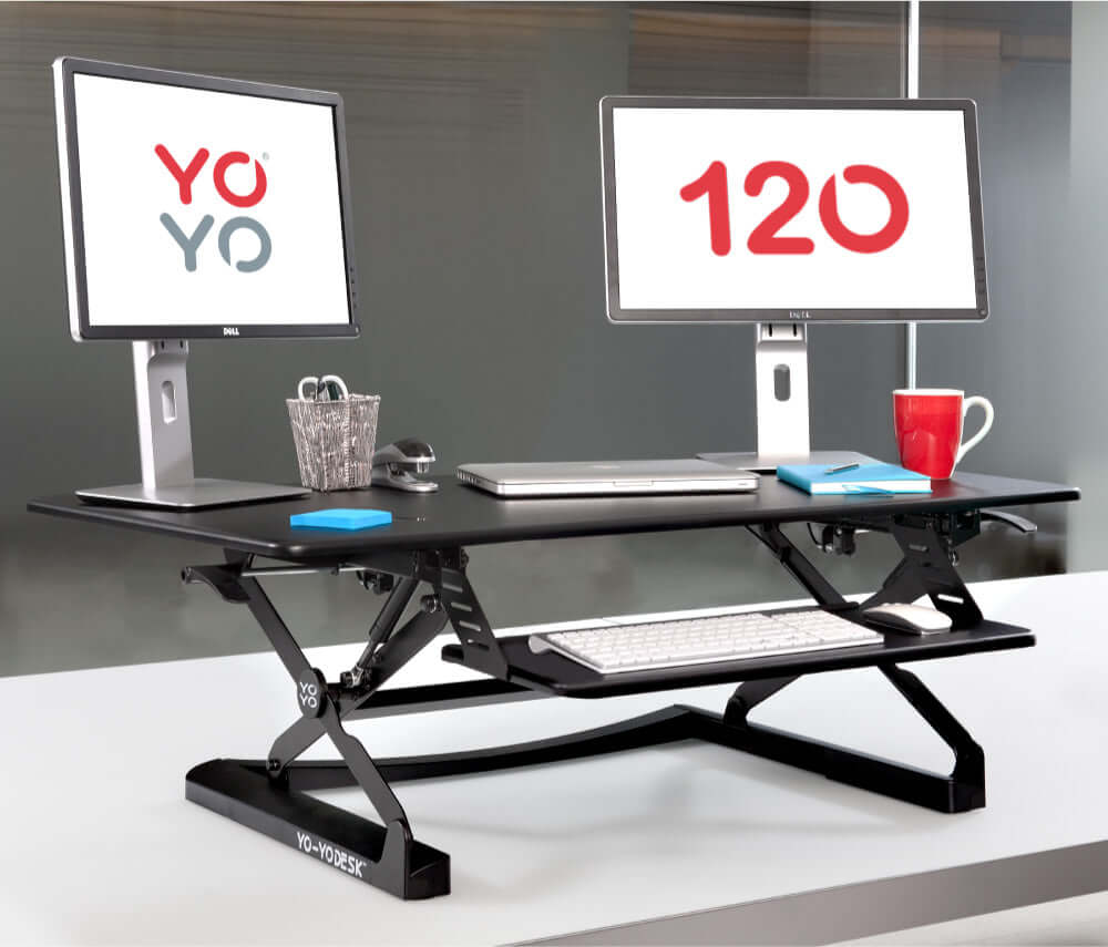 Dual monitor standing desk converter with adjustable height and ergonomic design in a modern office setting.